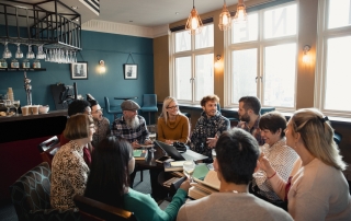 group of people sitting in a circle with books in front of them