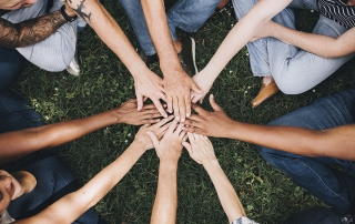 People stacking hands together in the park