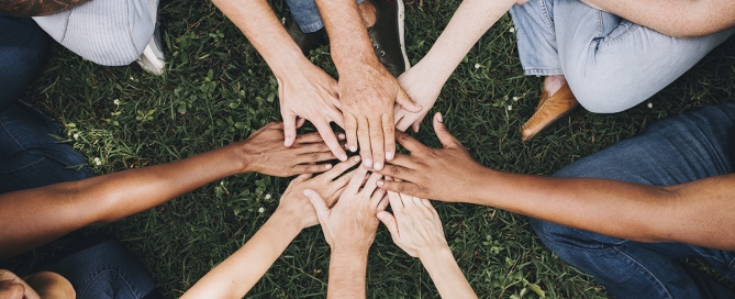 People stacking hands together in the park