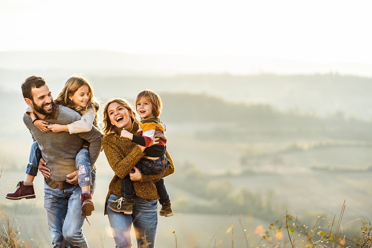 Young happy family enjoying in autumn walk on a hill.