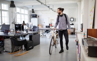 Businessman with a bicycle in office. Business professional going home after work.