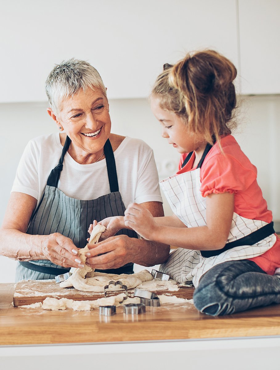 Senior woman and small girl preparing cookies together in a kitchen