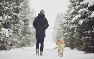 man walking outside in winter with dog