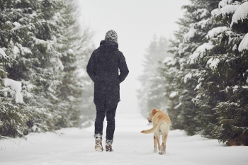 man walking outside in winter with dog