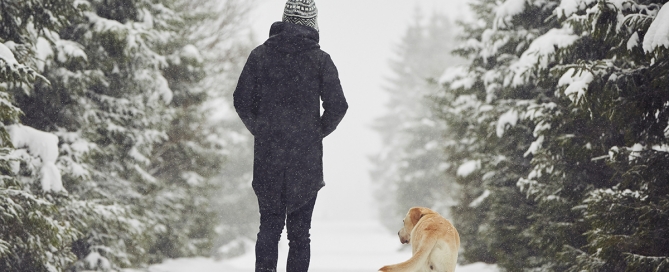 man walking outside in winter with dog