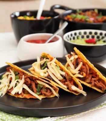 image of three tacos on a plate with salsa and guacamole on the side